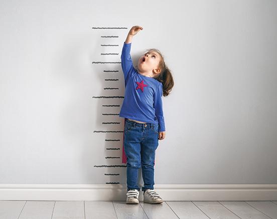 An image of a small girl standing against a wall, measuring her height