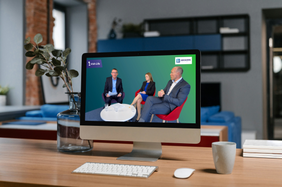 A computer screen shows two men and a women sitting around a table talking