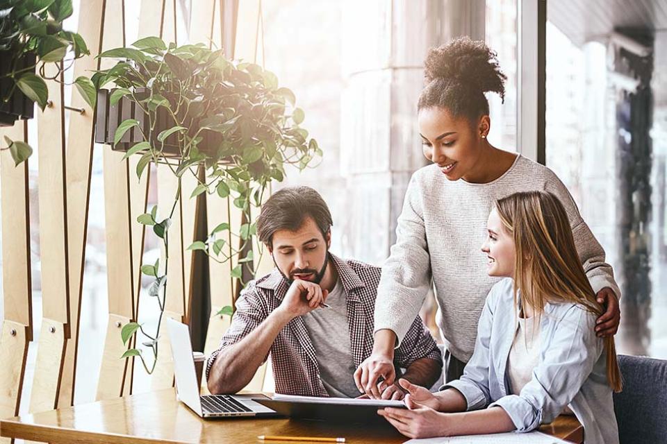 Three young professionals looking at printed information