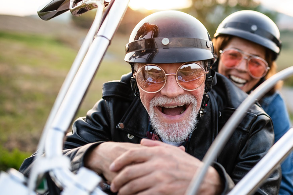 older couple sitting on a stationary motorbike, smiling