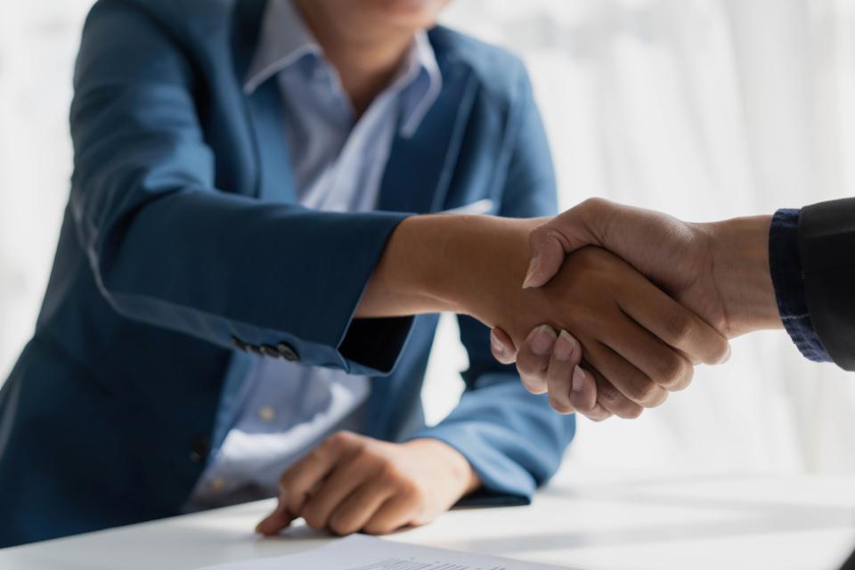A photo of two people shaking hands across a desk