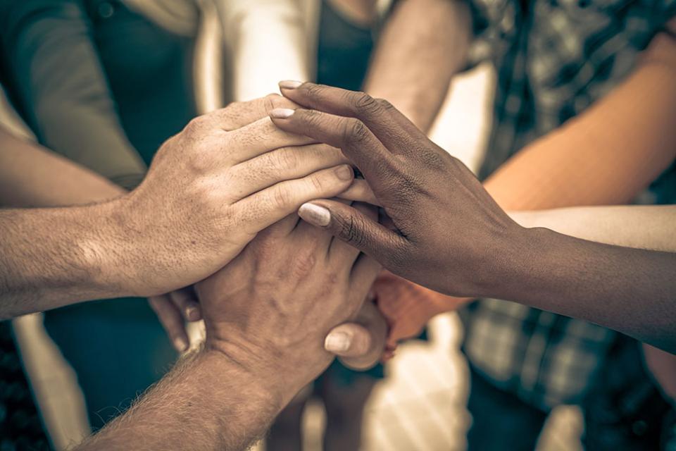 Image of hands from a diverse range of ethnic groups stacked on one another